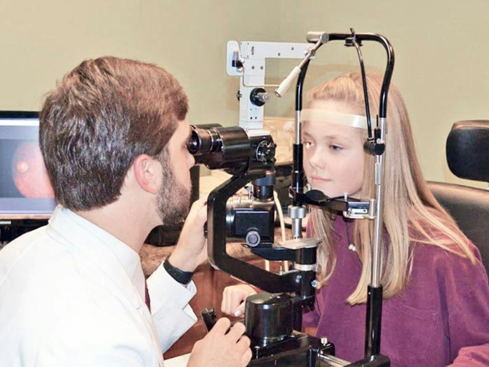 An optometrist checking a young woman&rsquo;s eyes with an examination instrument